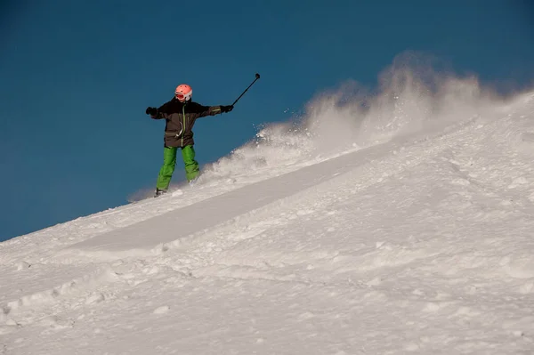 Сноубордист їде по схилу з камерою в руках — стокове фото