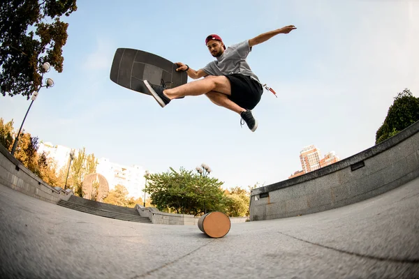 Fish-eye shot from below man making trick on the balance board on the concrete border — Stock Photo, Image