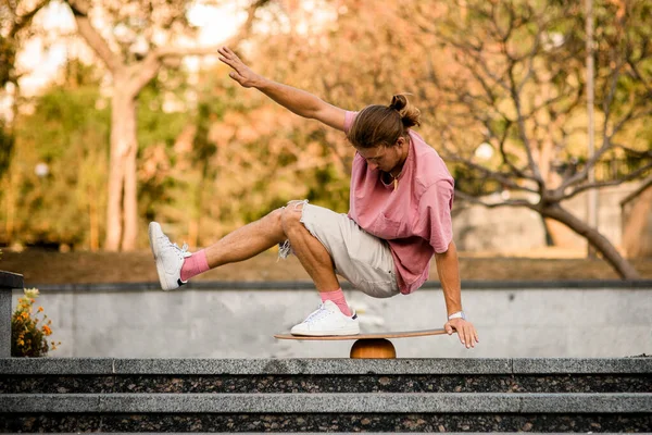 Homem que equilibra agachamento no tabuleiro de equilíbrio nas etapas de concreto no parque — Fotografia de Stock