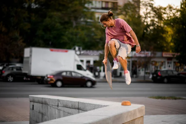Man springt met het balansbord in de hand op de betonnen grens in de stad — Stockfoto