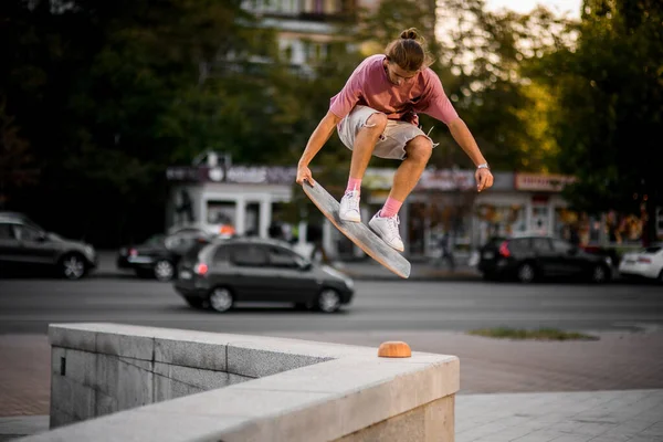 Boy jumping with the balance board in hand on the concrete border in the town — Stock Photo, Image