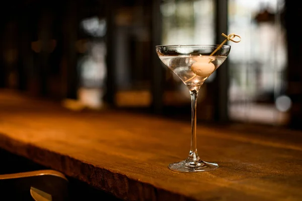 Heerlijke alcoholische cocktail in het glas versierd met een witte bal op de spies op de houten bar teller — Stockfoto