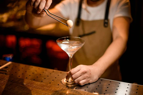 Professionell bartender lägga till en vit boll till cocktail i glaset med pincett — Stockfoto