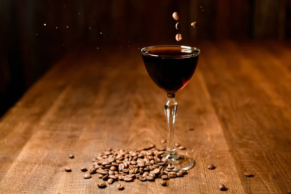 커피 원두와 나무 탁자 위에 서 있는 갈색의 칵테일 — 스톡 사진