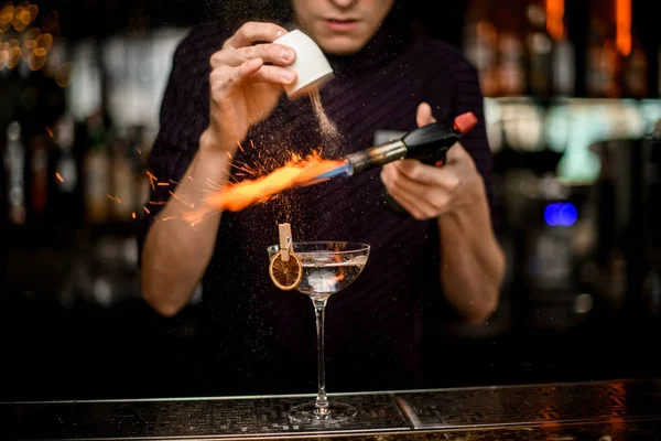 Barman profissional adicionando a um coquetel alcoólico nas especiarias de vidro e queimando-os — Fotografia de Stock