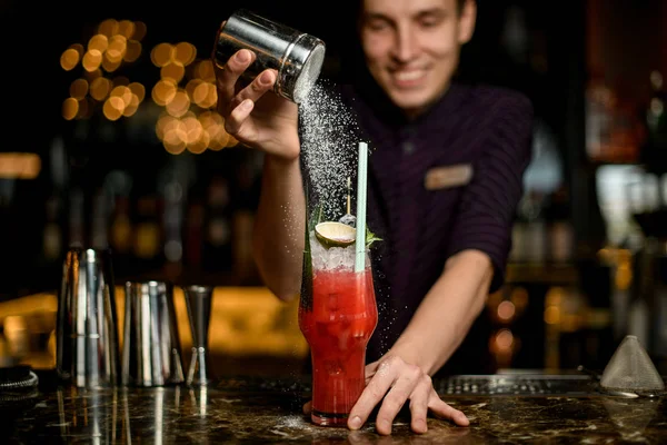 Barman besprenkelt aan het cocktailglas versierd met ijs, kalk en tropisch blad een suikerpoeder — Stockfoto