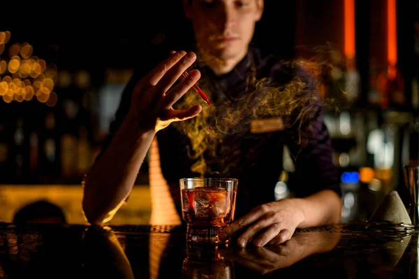 Professionelle Barkeeper Tropfen eine Essenz zu einem Glas mit Cocktail mit Eis im Rauch — Stockfoto