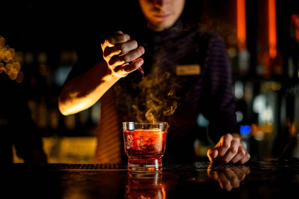 Barkeeper Tropfen eine Essenz in ein Glas mit Cocktail mit Eis im Rauch — Stockfoto