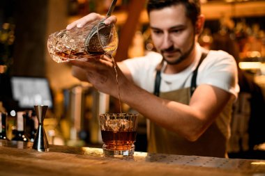 Barmen süzgeç ile camdan alkol döküyor