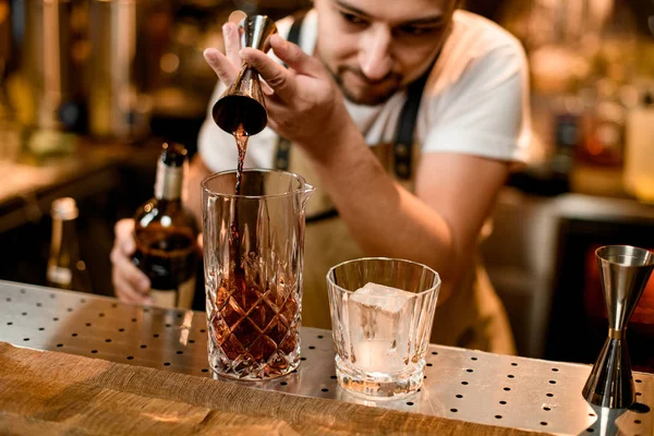 Bartender pours alcohol from jigger to glass — 스톡 사진