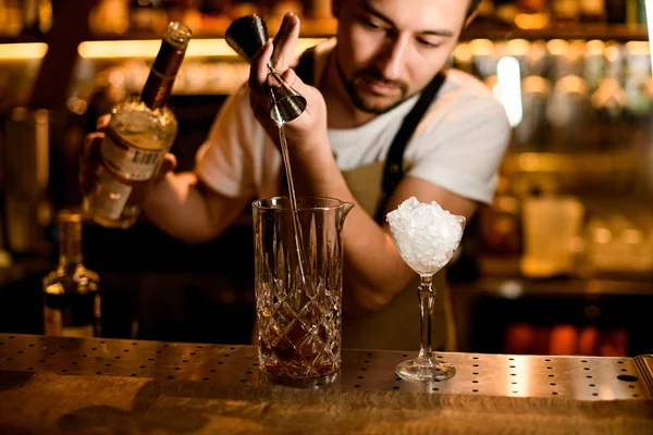 Barman nalévá čerstvý alkohol z jiggeru do karafy — Stock fotografie