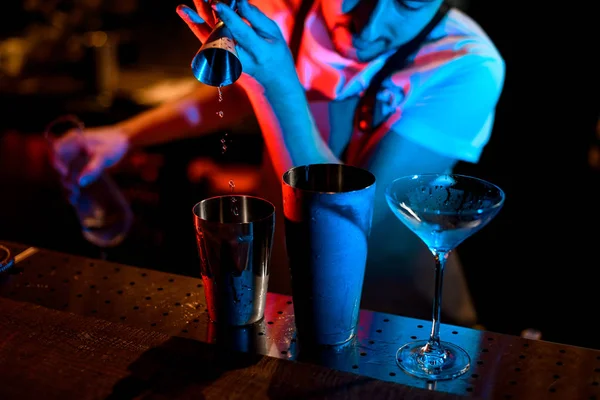 stock image Bartender pouring cocktail with jigger in neon lights