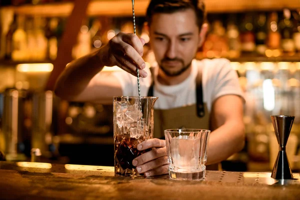 Barman miesza alkohol z lodem w szklance — Zdjęcie stockowe