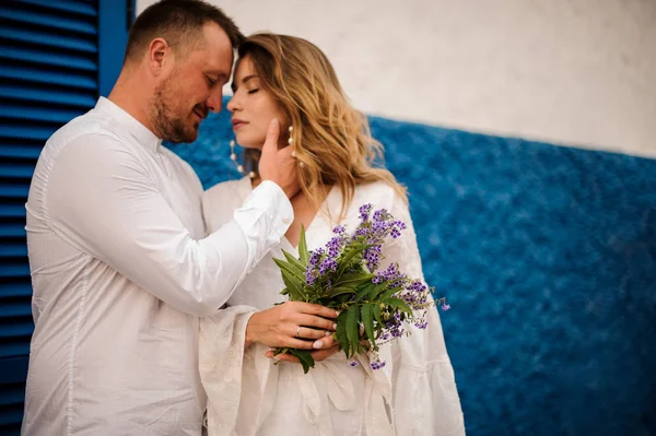 Bräutigam und Braut umarmen sich vor halb blauer halb weißer Wand — Stockfoto