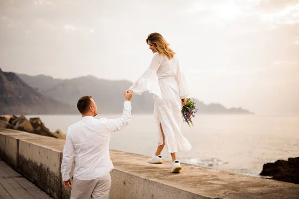 Noivo masculino e noiva feminina com um buquê andando na ponte de mãos dadas — Fotografia de Stock