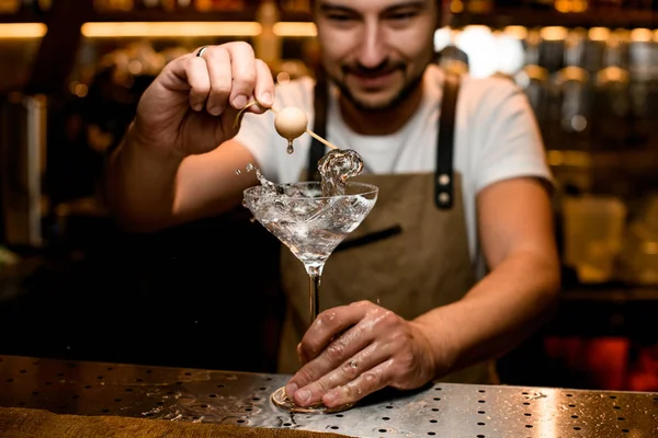 Man bartender lägga till en vit boll på spett till cocktail i glaset med ett stänk — Stockfoto