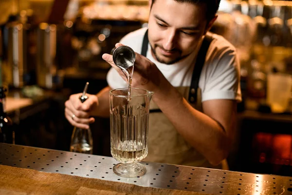 Barman derramando uma bebida alcoólica do jigger para um copo de vidro de medição — Fotografia de Stock