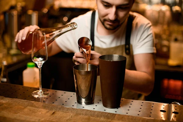 Barman verser une boisson alcoolisée orange de la gigue à un shaker en acier brun — Photo