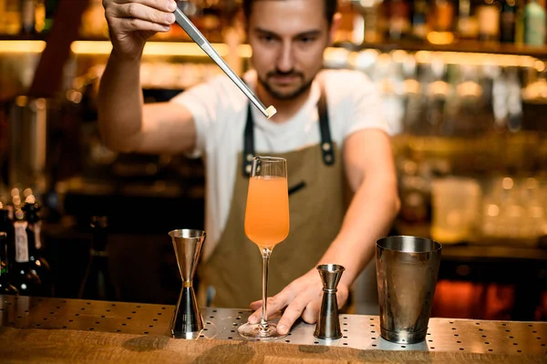 Profesyonel erkek barmen cımbızla bardağa şeker küpü ekliyor. — Stok fotoğraf