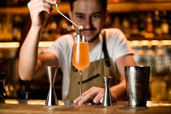 Professionele barman voegt met pincet een beetje suikerklontje toe aan een cocktail in het glas — Stockfoto