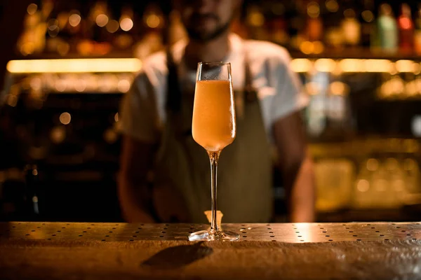 Professionele mannelijke barman serveert oranje gele cocktail in het hoge glas — Stockfoto