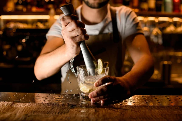 Barman profissional fazendo um coquetel com limão e bebida alcoólica com um empurrador — Fotografia de Stock