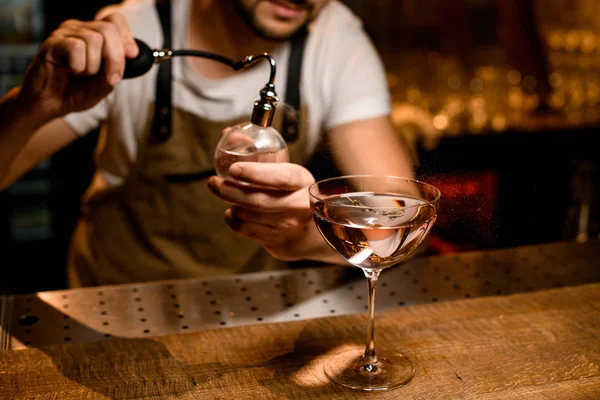 Професійний чоловічий бармен розбризкує на коктейлі в склянці з гірким — стокове фото