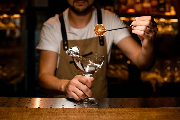 Manlig bartender tillsätter till en alkoholhaltig cocktail en torkad citron med pincett — Stockfoto