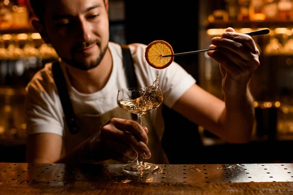 Barista aggiungendo a un cocktail alcolico una fetta di limone essiccata con pinzette — Foto Stock