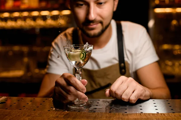Professionell bartender blandar med stänk en alkoholhaltig cocktail med en gurkskiva — Stockfoto