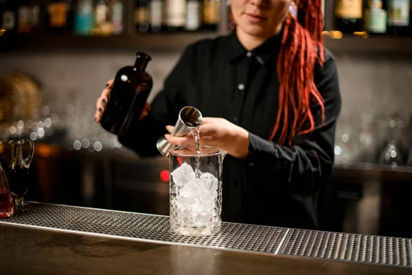 Barman derrama álcool de garrafa com jigger — Fotografia de Stock