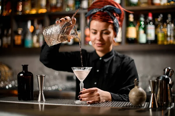 Garota barman derramando uma bebida alcoólica do copo de medição para um copo de coquetel — Fotografia de Stock