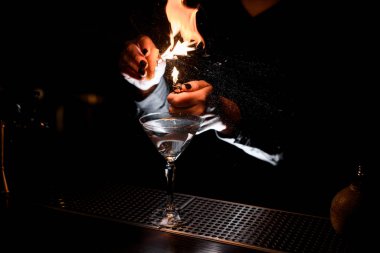 Alkollü bardağa portakal suyu serpiştiren ve aydınlatan kadın barmen.