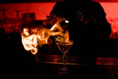 Kadın barmen, bardakta alkollü kokteyl servisi yapıyor. Şişte çiçek var.