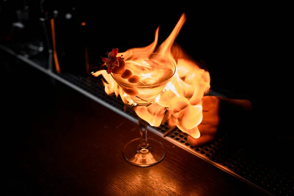 Female bartender serving cocktail in the glass in the fire around — Stock Photo, Image