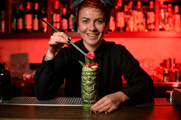 Garota de barman sorridente que serve coquetel alcoólico na caneca Tiki adicionando surgiu botão com pinças — Fotografia de Stock