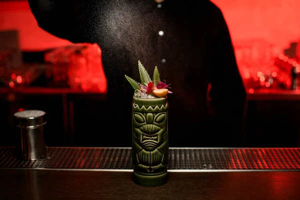 Barman girl servant un cocktail alcoolisé dans la tasse Tiki saupoudrer dessus avec de la poudre de sucre — Photo