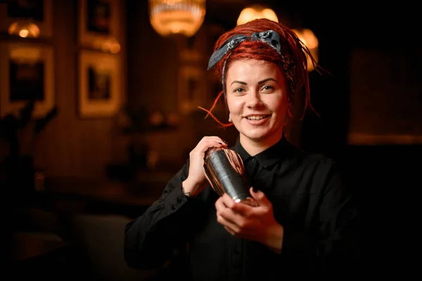 Bonito sorridente ruiva garçom com dreadlocks de pé no bar com uma coqueteleira de aço — Fotografia de Stock