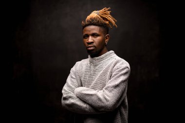 Black man with blonde dreadlocks posing with crossed arms