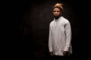 Siyah arka planda poz veren Afro-Amerikalı adam.