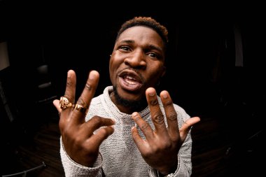 Afro-Amerikalı adam kameraya agresif bir şekilde rap yapıyor.
