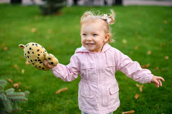 Niña sonriente corriendo en el parque de otoño con un juguete punteado negro amarillo en sus manos — Foto de Stock