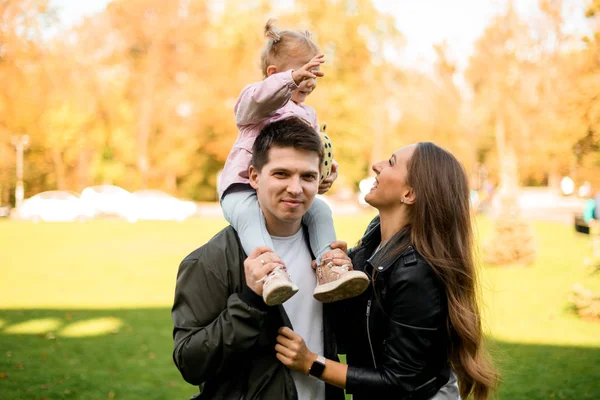 아버지 어깨에 어린 딸을 안고 가을 공원에서 있는 행복 한 가족 — 스톡 사진