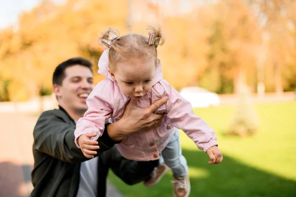 Apa játszik a lányával, felemelkedik egy karú babával. — Stock Fotó