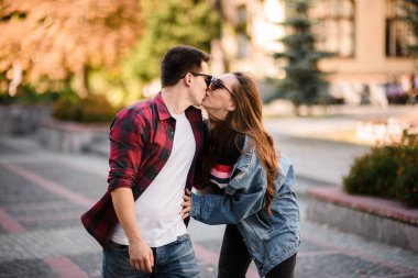 Mutlu romantik çift sonbahar parkında el ele tutuşup öpüşüyor.