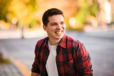 Sonbahar parkında duran genç bir adamın portresi.