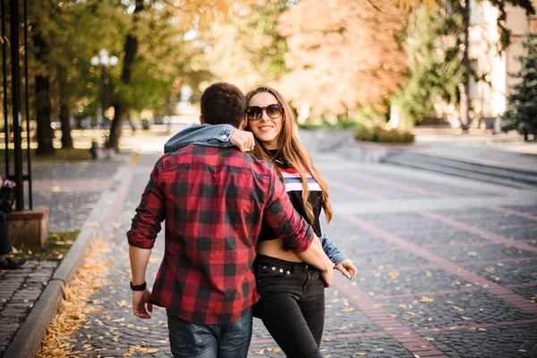 Sonbahar parkında yürüyen romantik bir çift ve sarılan bir erkek. — Stok fotoğraf