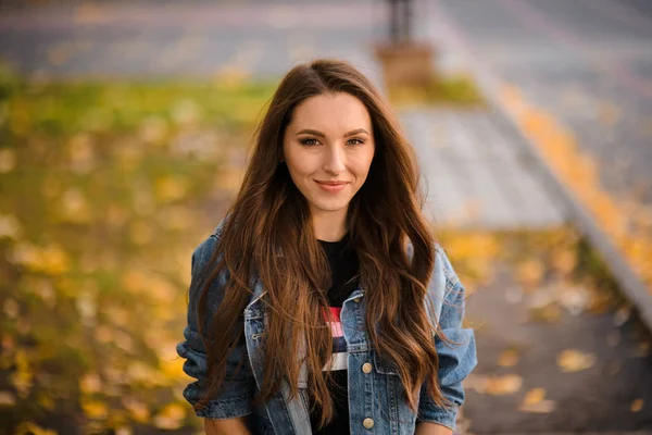 Portret van een jonge vrouw op de straatstenen met gele bladeren in het herfstpark — Stockfoto