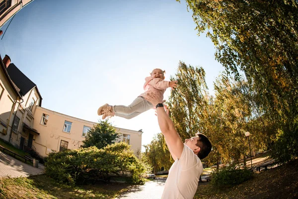 Fish-eye photo father playing with daughter tossing her up