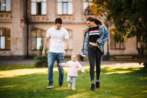 Moeder en vader rennen met een dochtertje in het park — Stockfoto